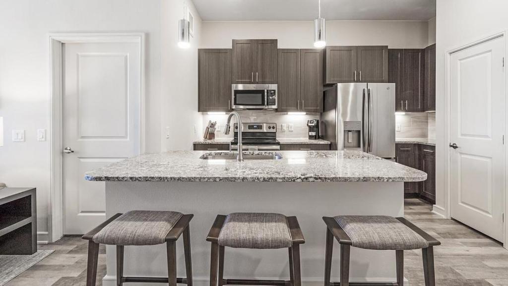 a kitchen with a large island with three stools at Landing Modern Apartment with Amazing Amenities (ID9874X53) in Dallas
