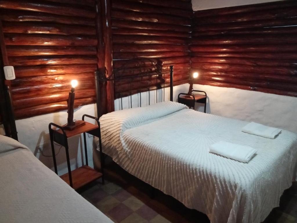 2 Betten in einem Zimmer mit Holzwänden in der Unterkunft dulce claudina in Mercedes