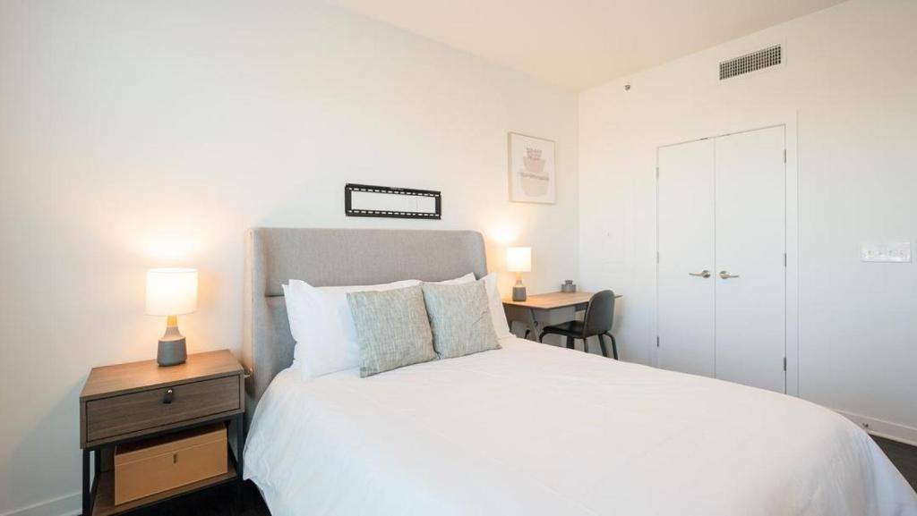 een slaapkamer met een wit bed en een bureau met een lamp bij Landing Modern Apartment with Amazing Amenities (ID8194X48) in Birmingham