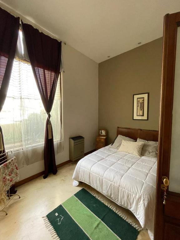 a bedroom with a bed and a window and a rug at La Casona de Blanca in Balcarce