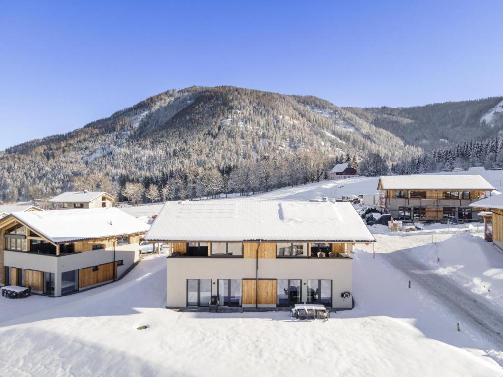 ein schneebedecktes Haus mit einem Berg im Hintergrund in der Unterkunft Grebenzen Lodge Pabstin 36B in Sankt Lambrecht