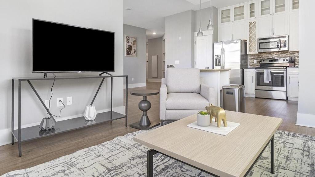 Landing Modern Apartment with Amazing Amenities (ID1014X909) في دورهام: غرفة معيشة مع تلفزيون بشاشة مسطحة وطاولة