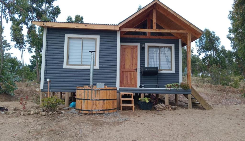 a blue tiny house with a porch and a bench at Cabaña Familiar La Polcura in Navidad