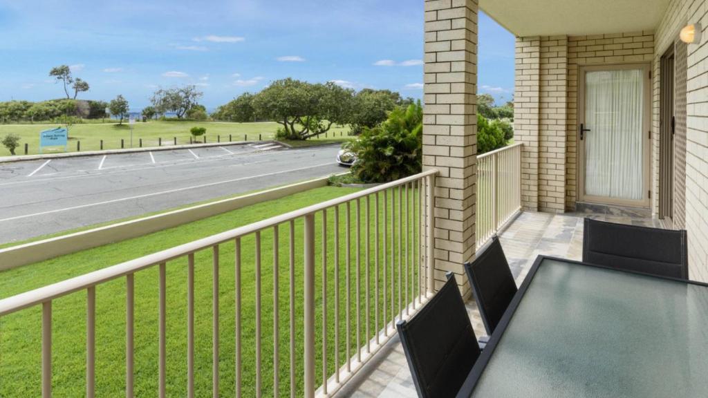 a balcony with a table and chairs and a street at Walk to Surf Beach - Ground floor apartment - Bribie Horizons Boyd St, Woorim in Woorim