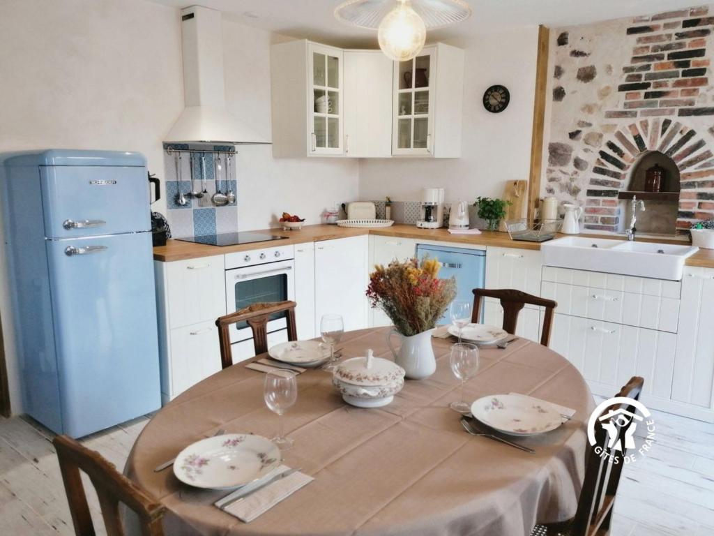 a kitchen with a table with chairs and a blue refrigerator at Gîte Sainte-Suzanne-et-Chammes, 3 pièces, 4 personnes - FR-1-600-192 in Sainte-Suzanne