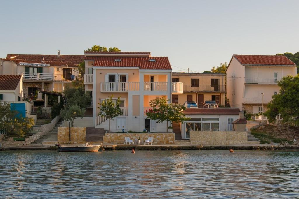eine Gruppe von Häusern am Wasser mit einem Boot in der Unterkunft Seaside house for families with children Rogoznica - 22156 in Rogoznica