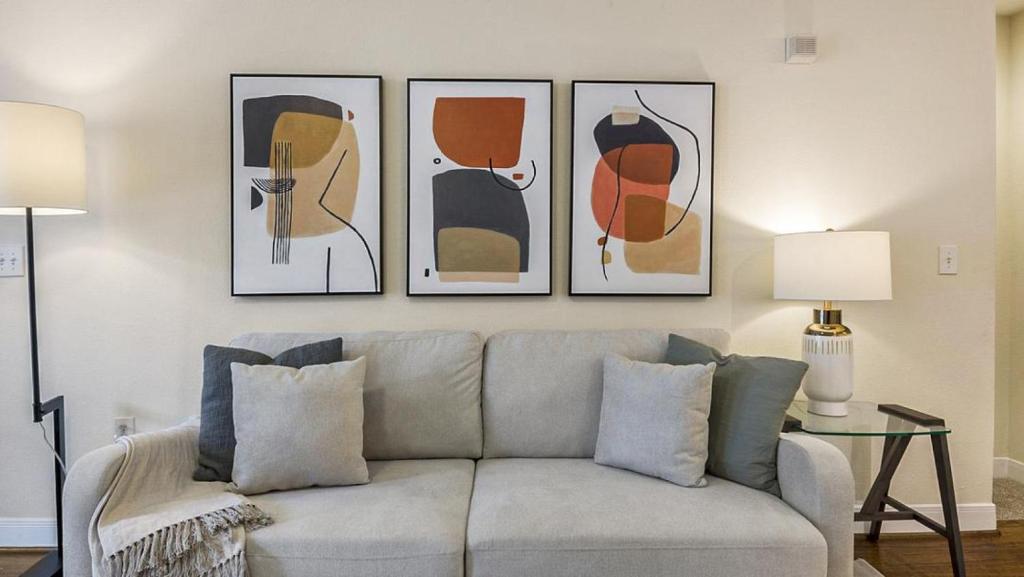 ein Wohnzimmer mit Sofa und vier Bildern an der Wand in der Unterkunft Landing Modern Apartment with Amazing Amenities (ID6447X41) in Houston
