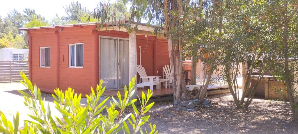 une petite maison rouge avec un banc et des arbres dans l'établissement Desconectate, à Balneario Argentino