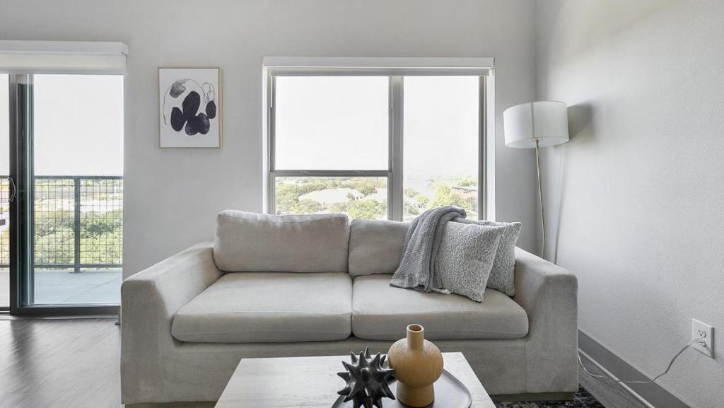 ein Wohnzimmer mit einem Sofa und 2 Fenstern in der Unterkunft Landing Modern Apartment with Amazing Amenities (ID7967X54) in Plano