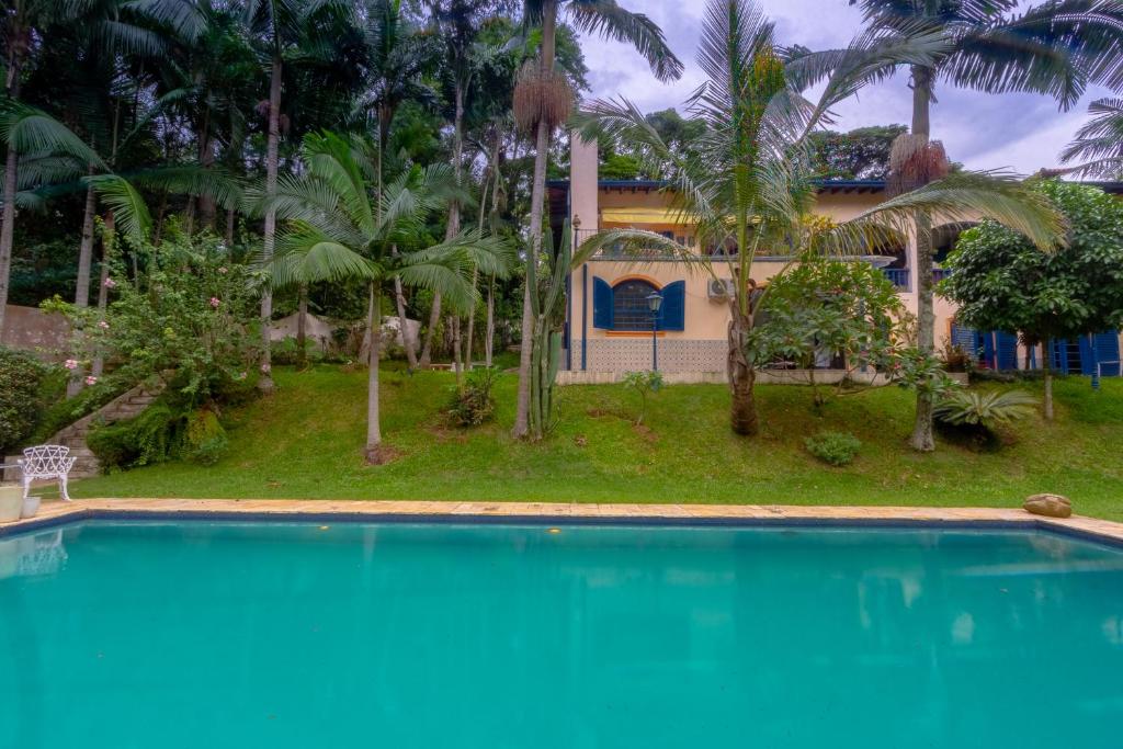 a swimming pool in front of a house with palm trees at Via Antiga Granja Viana in Cotia