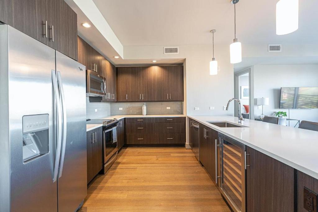 Landing Modern Apartment with Amazing Amenities (ID512) في دالاس: مطبخ مع دواليب خشبية وثلاجة حديد قابلة للصدأ