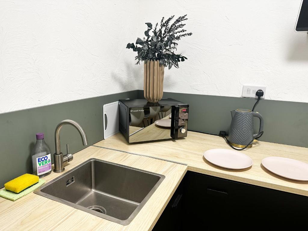 a kitchen counter with a sink and a microwave at Flat 1 Stay In Aldgate in London