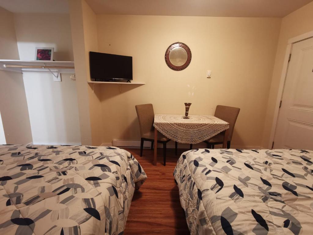 a room with two beds and a table and a television at Coquihalla Motel in Hope