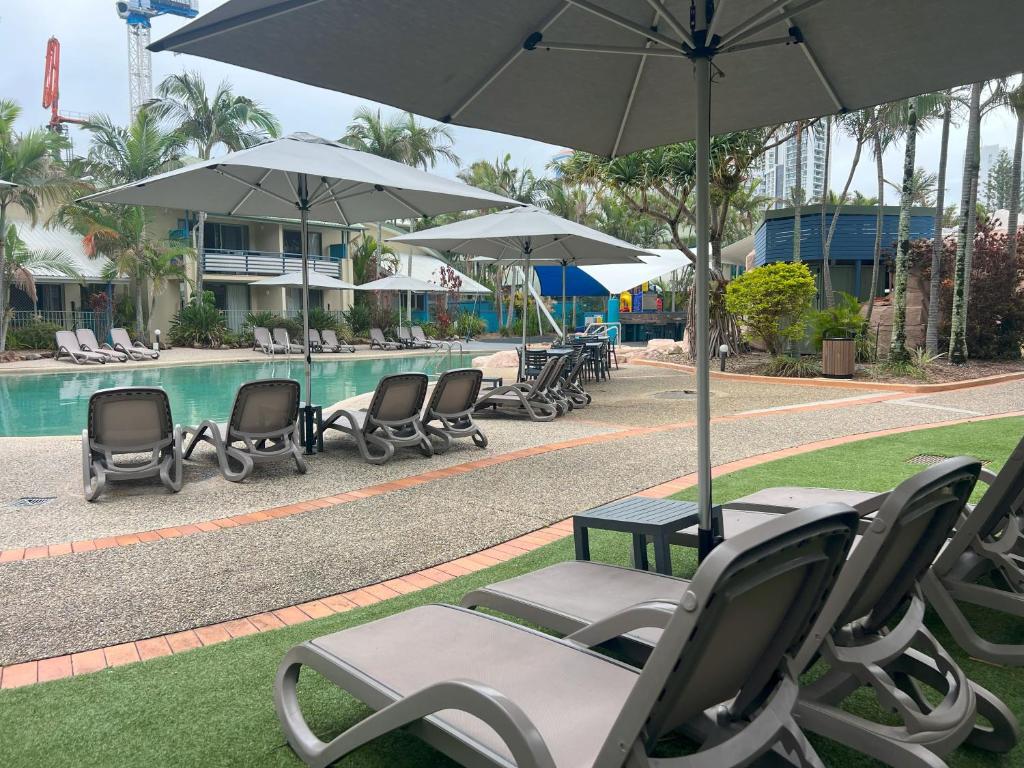 a group of chairs and umbrellas next to a pool at CHA Private Apts Diamond Beach in Gold Coast