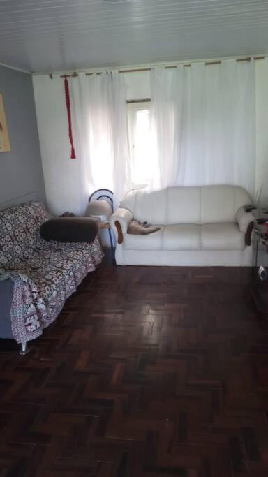 a room with a white couch and a window at Casa - ótima localização in Capão da Canoa