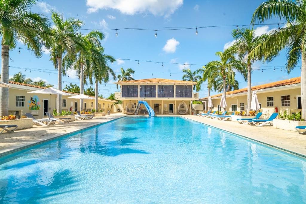 a swimming pool with palm trees and a resort at DeLynne Resort Curaçao in Willemstad