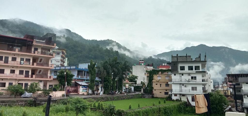 a city with buildings and a green field in front of mountains at Deepak Homestay in Rishīkesh