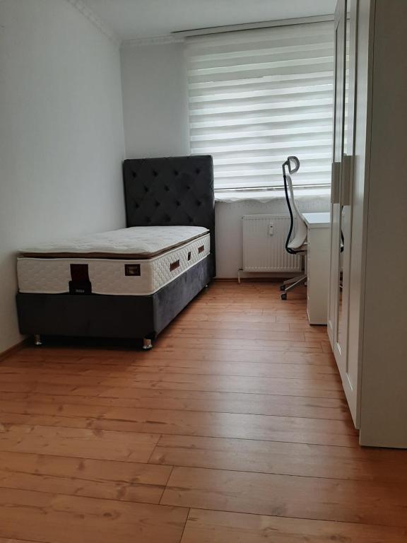 1 dormitorio con 1 cama y 1 silla junto a una ventana en A cozy room with brand new furniture, en Frankfurt