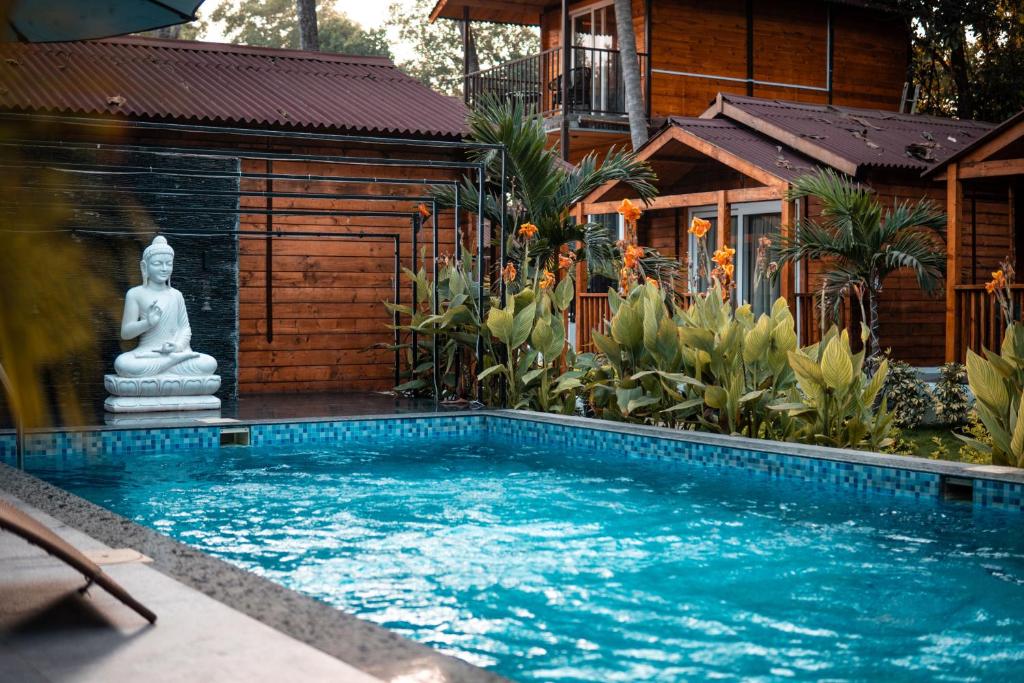 - une piscine en face d'une maison dotée d'une statue de buddha dans l'établissement Tranquill Riverside Luxury Cottages With Bathtub, Candolim, à Candolim