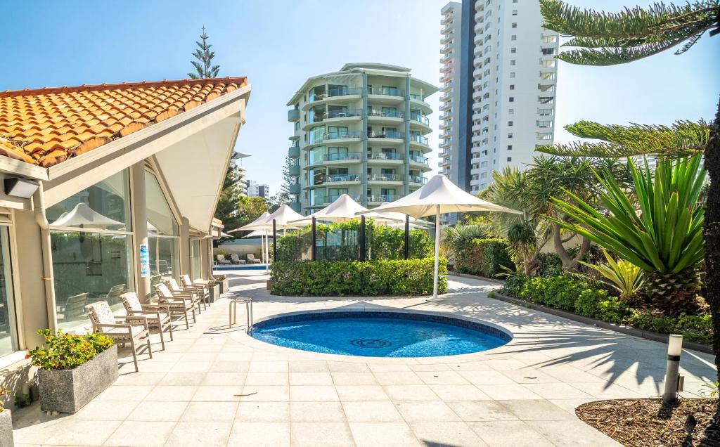 a swimming pool with chairs and umbrellas next to a building at Surfers Aquarius on the Beach in Gold Coast