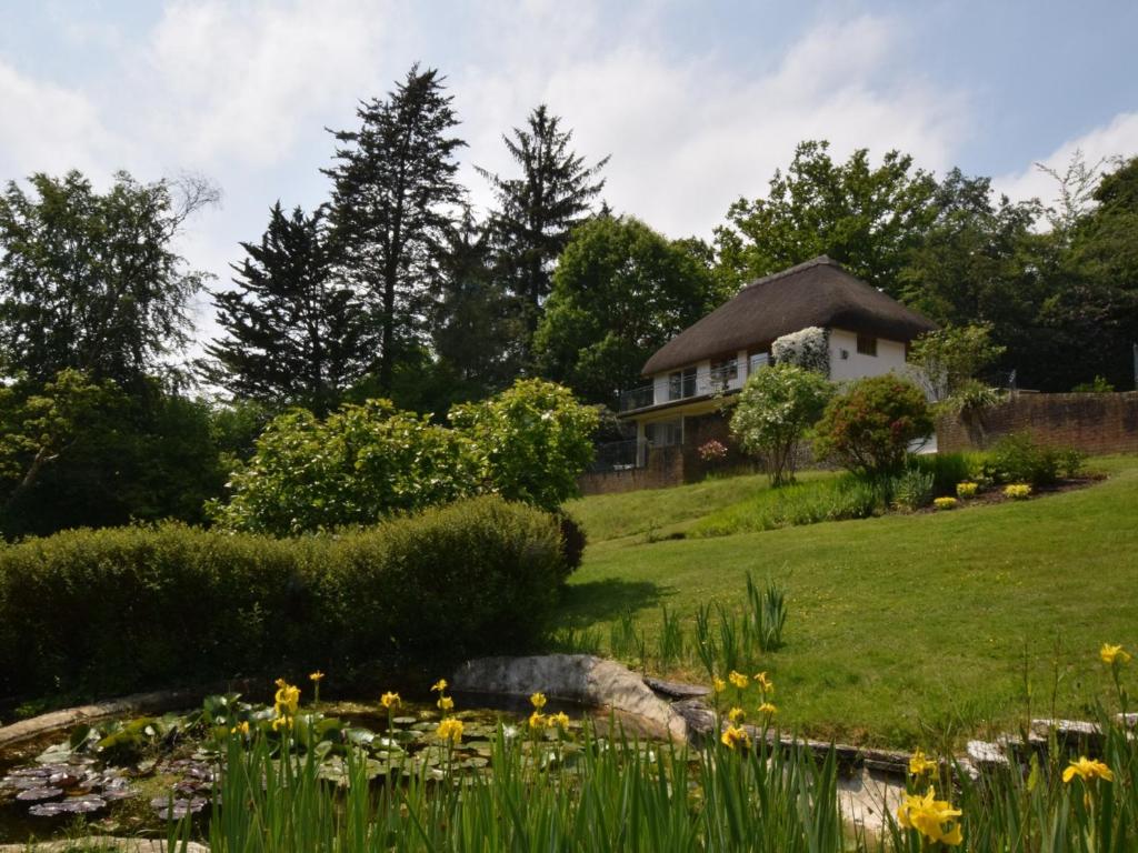 uma casa numa colina com um jardim e um lago em 3 bed property in Godshill New Forest 56431 em Godshill