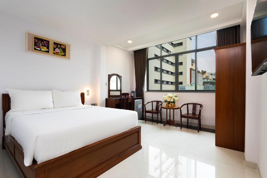 Un dormitorio con una gran cama blanca y una mesa en HOÀNG HOTEL, en Ho Chi Minh