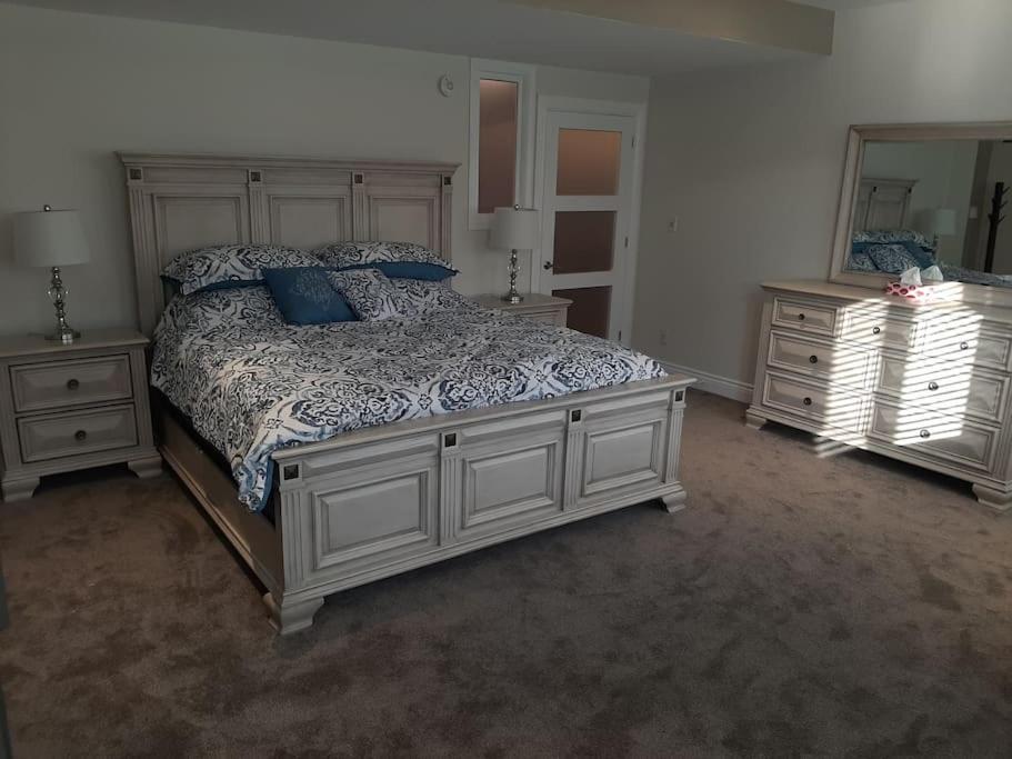 ein Schlafzimmer mit einem Bett, zwei Kommoden und einem Spiegel in der Unterkunft King guest apartment in Ottawa
