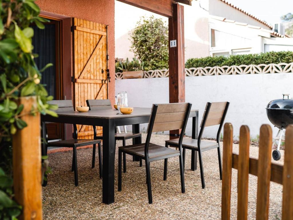 une table noire et des chaises sur une terrasse dans l'établissement Villa 2-pièces au calme avec mezzanine, terrasse et parking - 5 couchages - Animaux acceptés - FR-1-409-130, à Narbonne