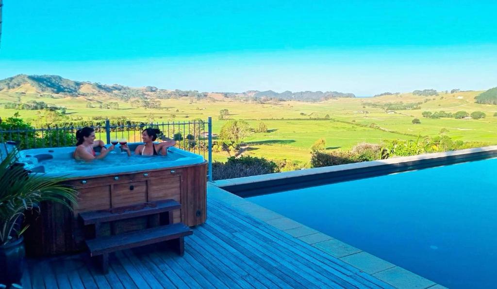 two people in a hot tub with a view of the mountains at Luxury Country retreat in Cooks Beach