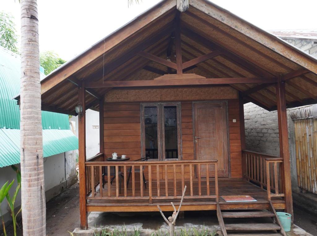 een klein houten huis met een veranda bij Rumah Tiga Gili #Panggung in Gili Air