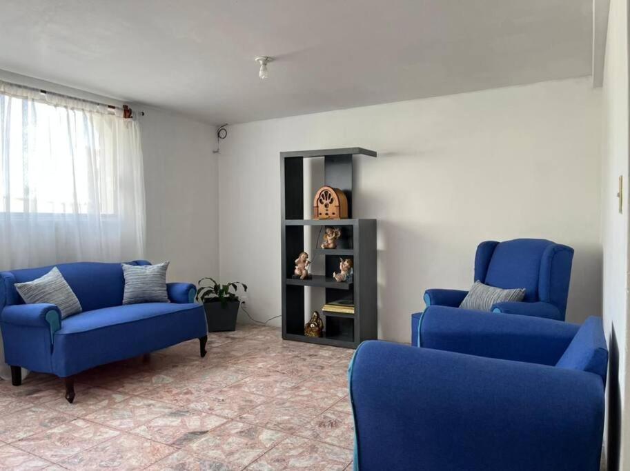 a living room with two blue chairs and a shelf at Hermoso departamento con Patio in Apizaco