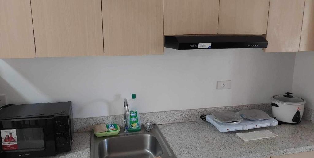 a kitchen with a sink and a microwave at SUNTRUST 88 GIBRALTAR - BAGUIO in Baguio