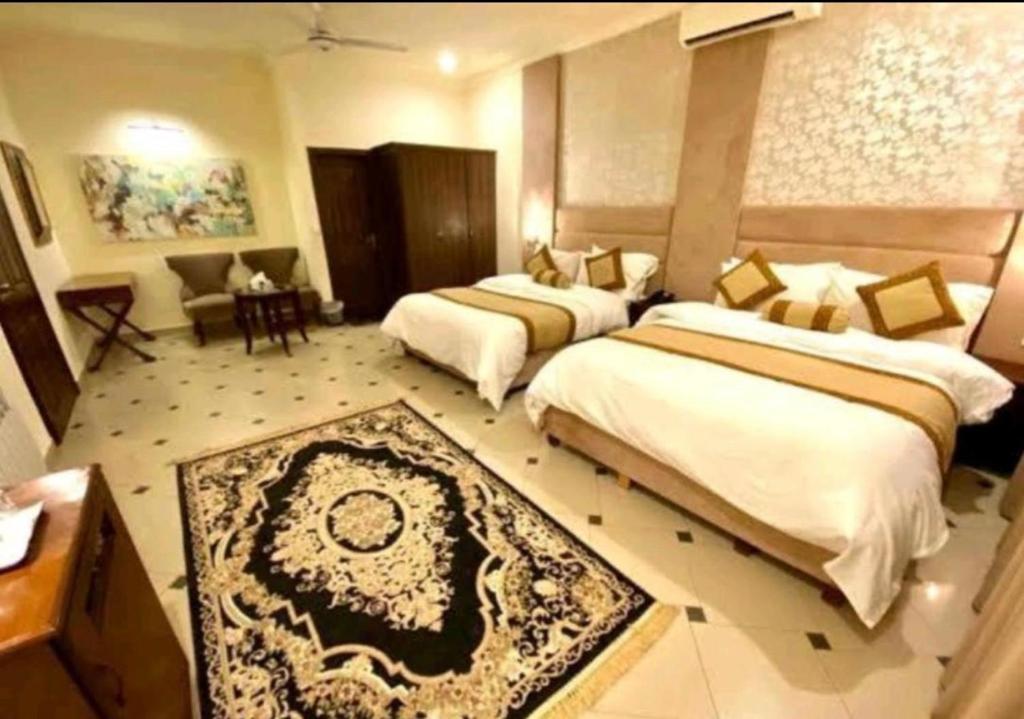 Cette chambre d'hôtel comprend deux lits, une table et des chaises. dans l'établissement Imperial Lodges, à Islamabad