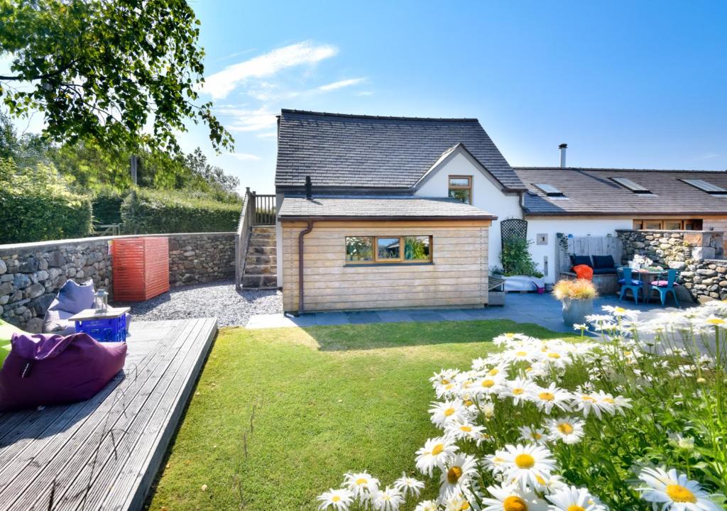 a house with a garden with flowers in the yard at Cysgu Llwynog in Llannor