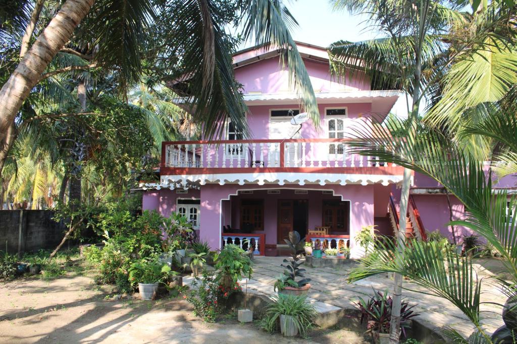 a pink house with a balcony and palm trees at El Shaddai in Mannar