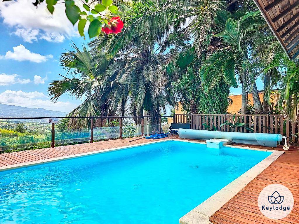 een zwembad met palmbomen op de achtergrond bij Verger suspendu - avec piscine - 100m2 - Étang-Salé les Hauts in Gôl