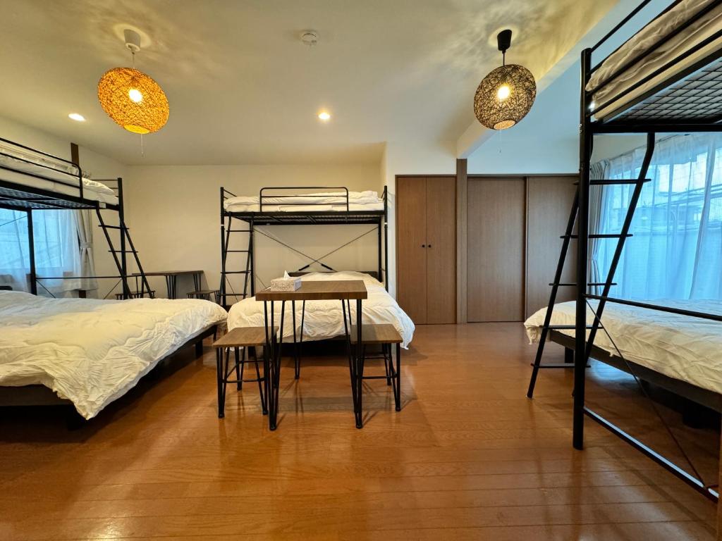 大阪市にあるExsaison 桃谷の二段ベッド2台、テーブル、椅子が備わる客室です。