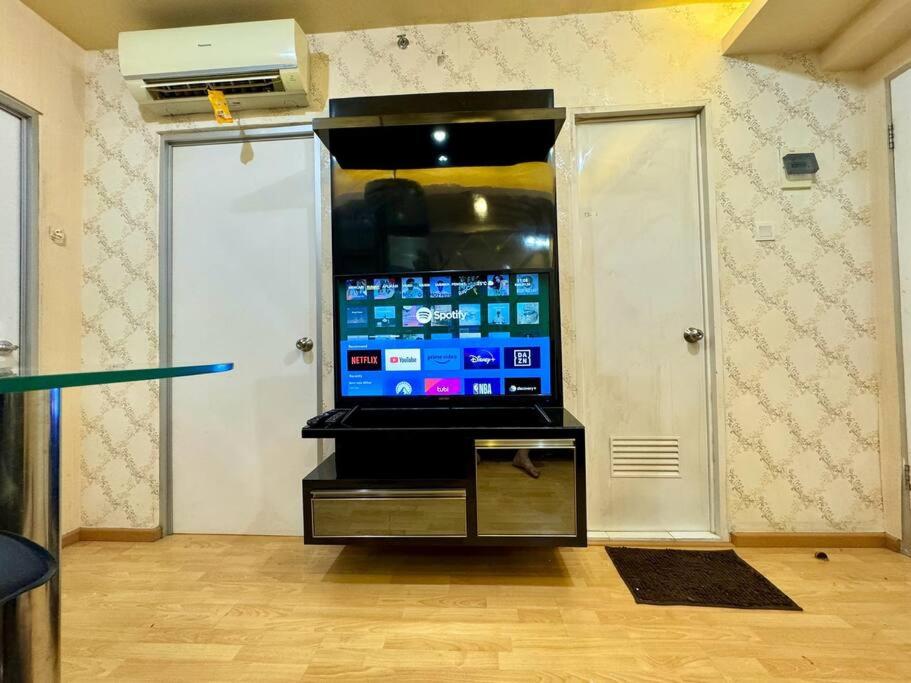 a large screen tv in a room with two doors at 2BR Luxury Cozy Homestay With Mall Access Greenbay Apartment Baywalk in Jakarta