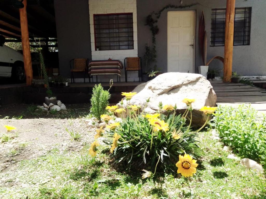 un jardin avec des fleurs jaunes devant une maison dans l'établissement Cabañas Ezequiel, à Villa Carlos Paz