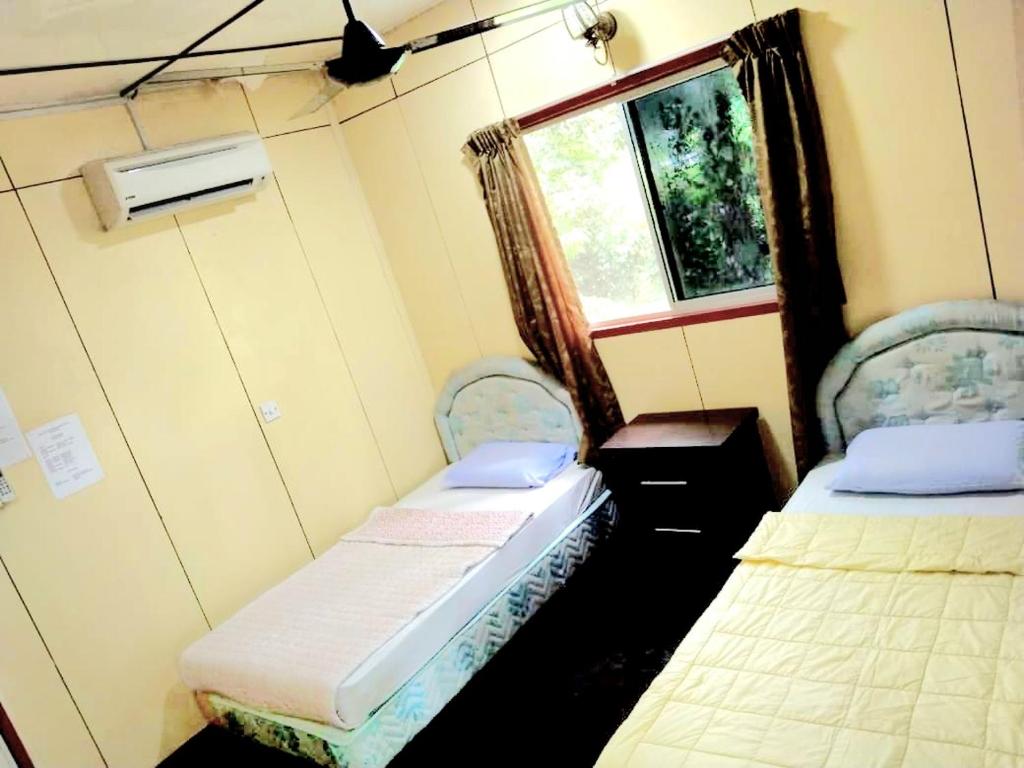 um pequeno quarto com 2 camas e uma janela em Sukau Backpackers B&B em Sukau