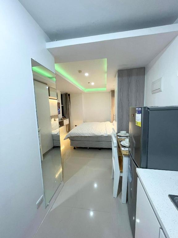 a room with a bed and a kitchen with a refrigerator at Studio Anna in Cebu City
