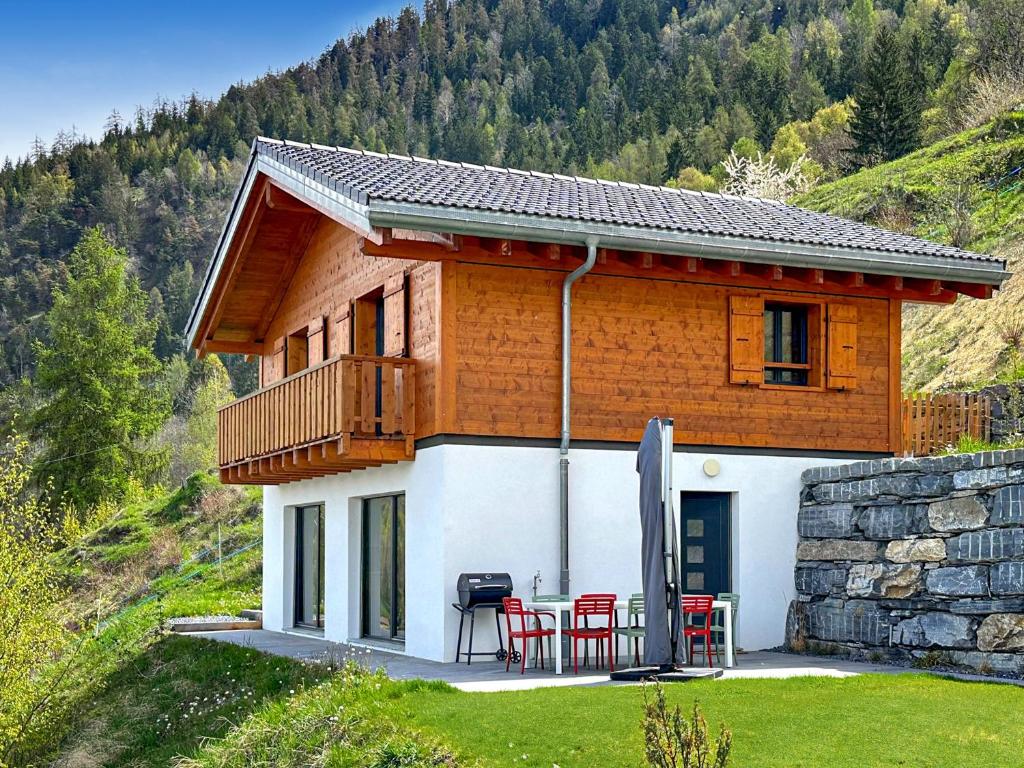 een huis met een tafel en stoelen ervoor bij My Mountain Paradise - Swiss Alps in Rechy