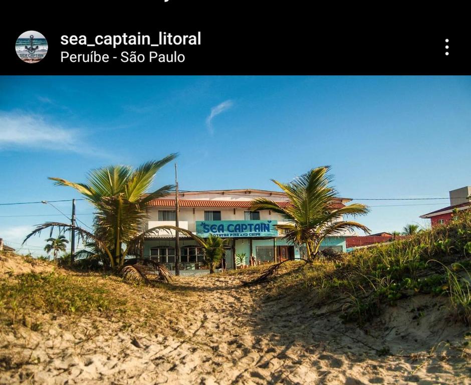 a building on the beach with palm trees in front at Sea Capitain Pousada e Restaurante in Peruíbe
