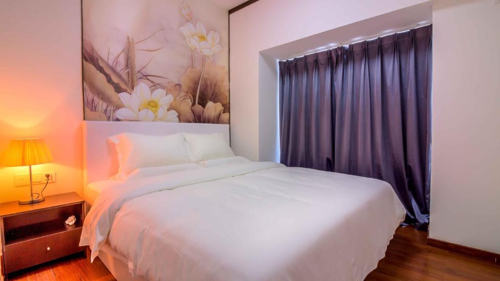 un dormitorio con una cama blanca y una pintura de flores en Pazhou Yi Xiu Boutique Apartment en Cantón