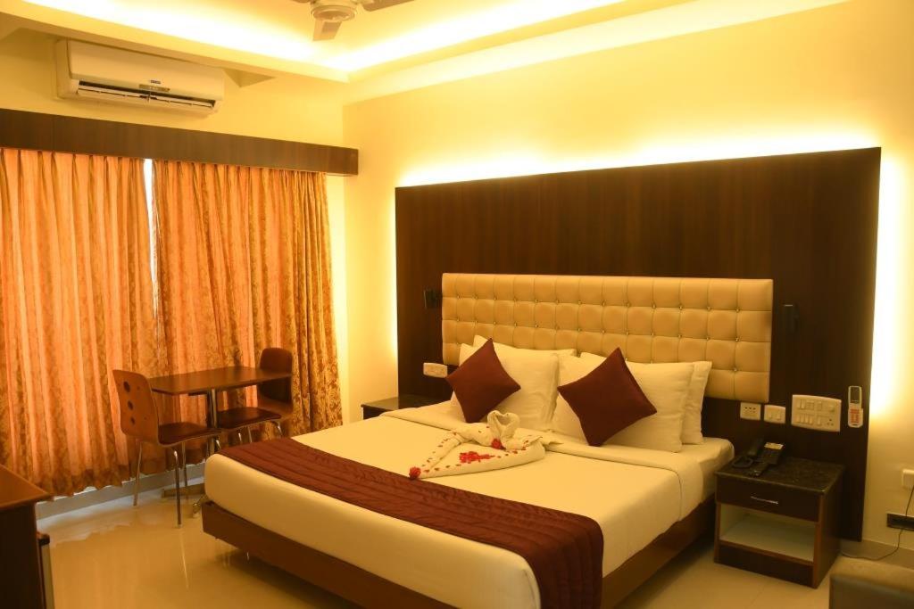 a hotel room with a large bed and a desk at Hotel SR Tiruchendur in Thiruchendur