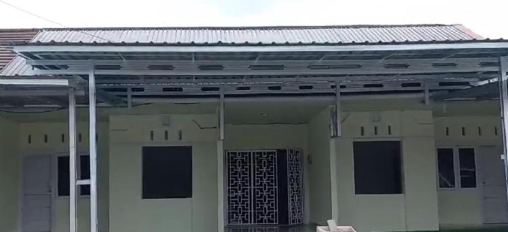 un grand bâtiment blanc avec un toit en métal dans l'établissement Lovetogy homestay, à Sungailiat