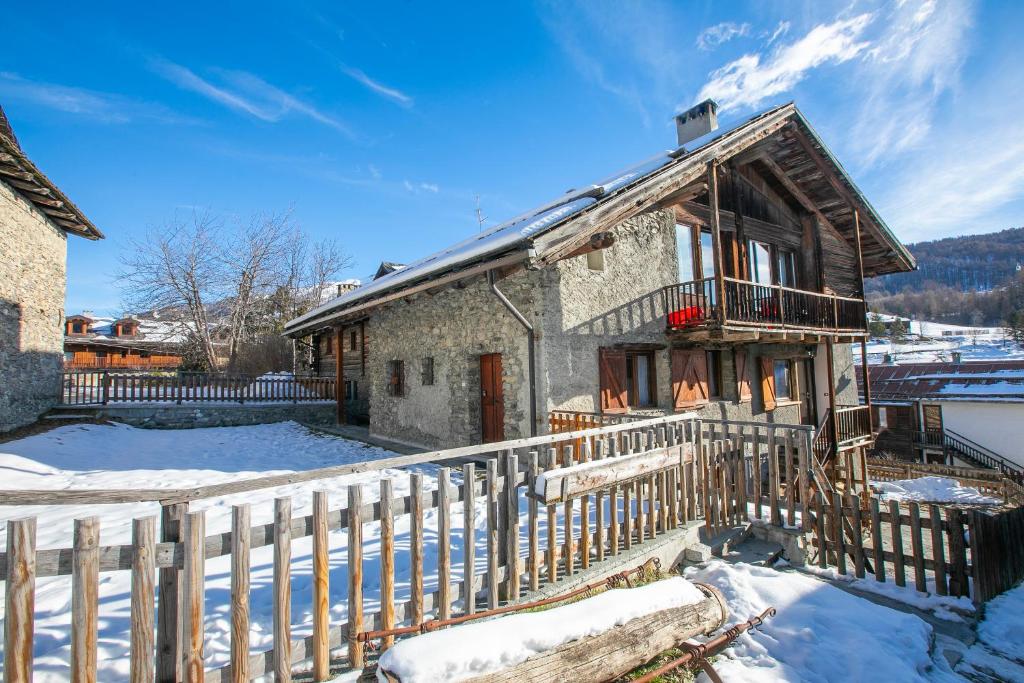 a stone house with a fence in the snow at Paquita's Home - San Sicario Borgo - Happy Rentals in Cesana Torinese