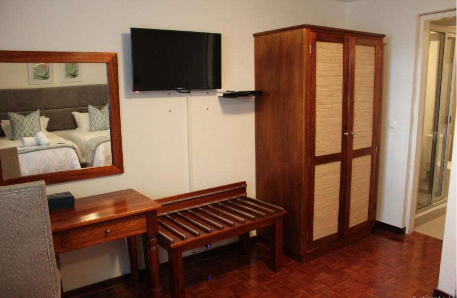 Zimmer mit einem Schlafzimmer mit einem Bett und einem Spiegel in der Unterkunft Ka maxakeni guesthouse in Maputo