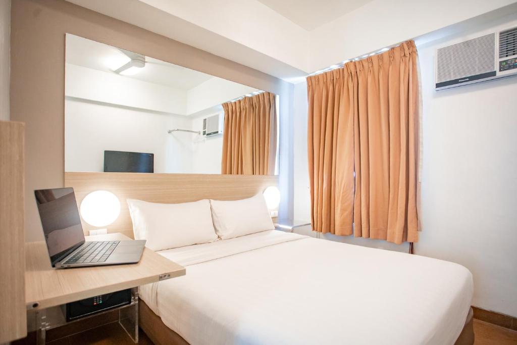 a bedroom with a bed with a laptop on a desk at Red Planet Cebu in Cebu City