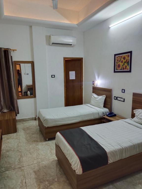 a hotel room with two beds and a mirror at Gulnaar Inn in Chennai